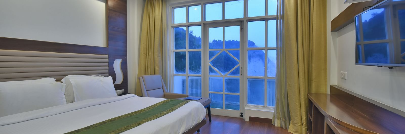 A view of a large bed next to a large bed in Premium Room at DLS Highland Resort and Spa, Mussoorie.